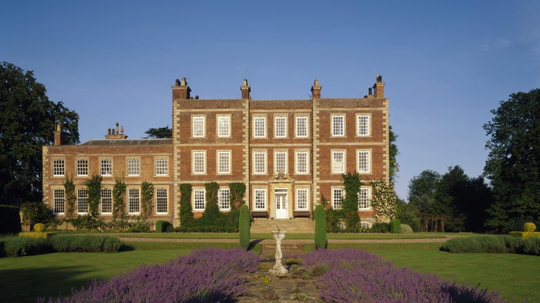 View of the front entrance of Gunby Hall with lavender borders and formal lawns in summer.